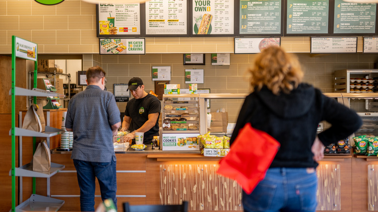 Customers wait in line at a Subway restaurant
