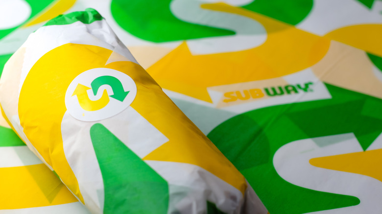 a wrapped 6-inch Subway sandwich atop additional branded sandwich-wrapping paper