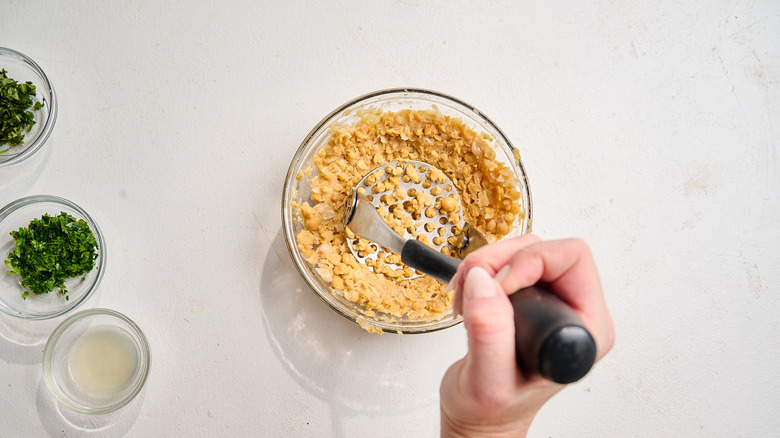 smashing chickpeas in a bowl