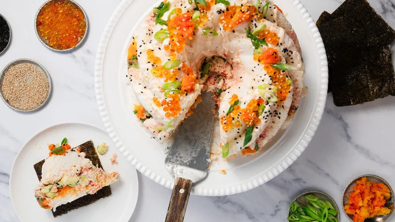 Aerial view of Bundt pan spicy crab sushi with one slice removed and placed on a plate with nori