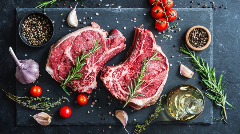 raw steak surrounding be fresh tomatoes and herbs