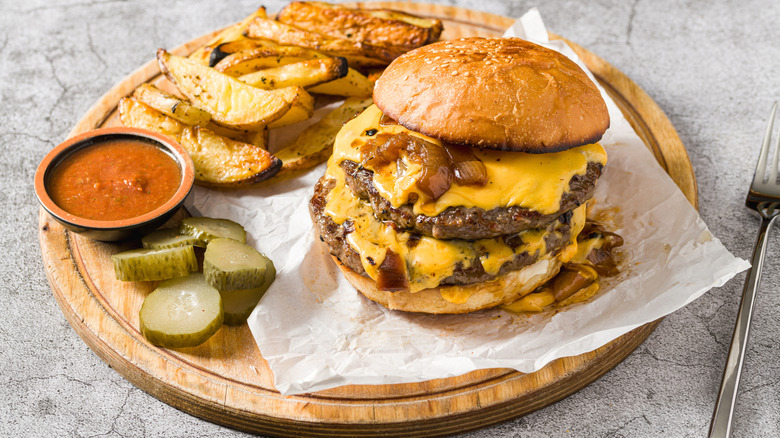 A double smash burger with wedge fries and pickles
