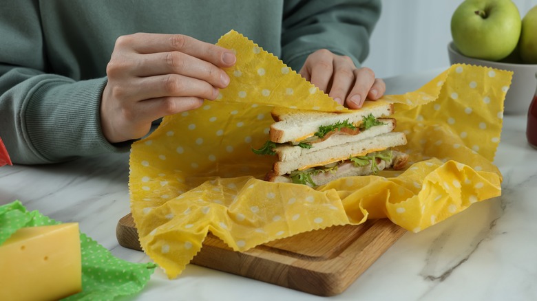 person wrapping sandwich in yellow beeswax wrap