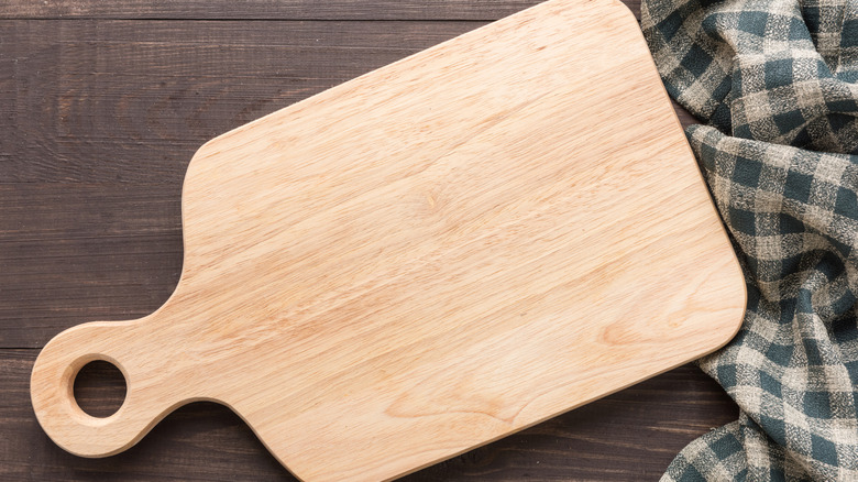 Cutting board with napkin on wooden background