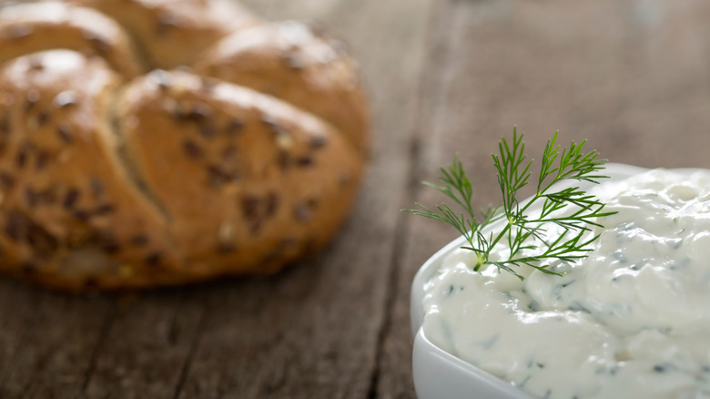 bowl of tzatziki with bagel in background