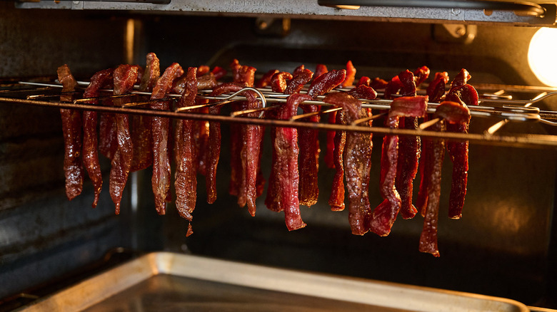 hanging beef jerky on skewers in the oven