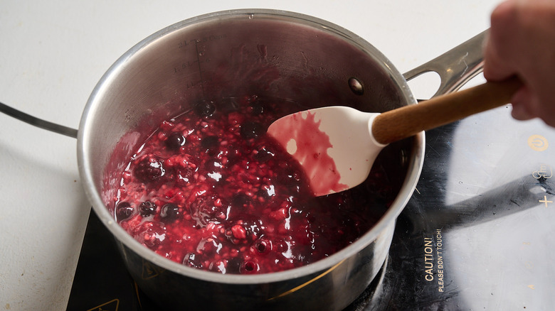 stirring berries in a saucepan with a spatula