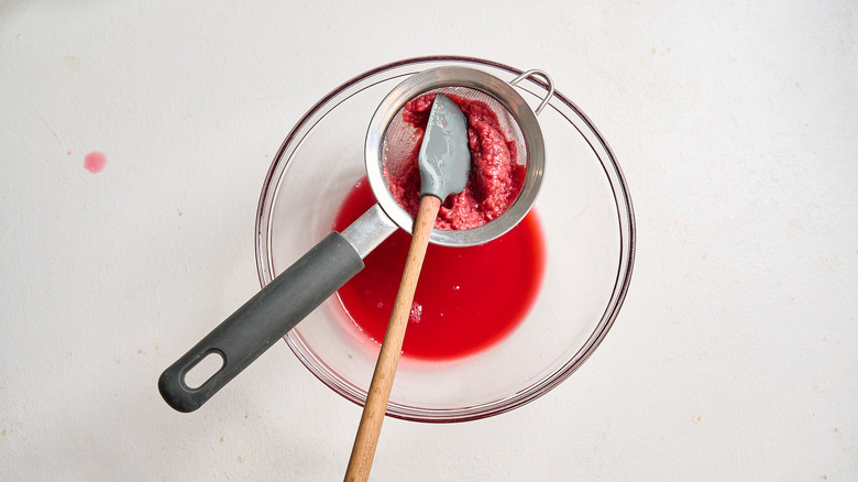 straining raspberry juice through a fine mesh sieve