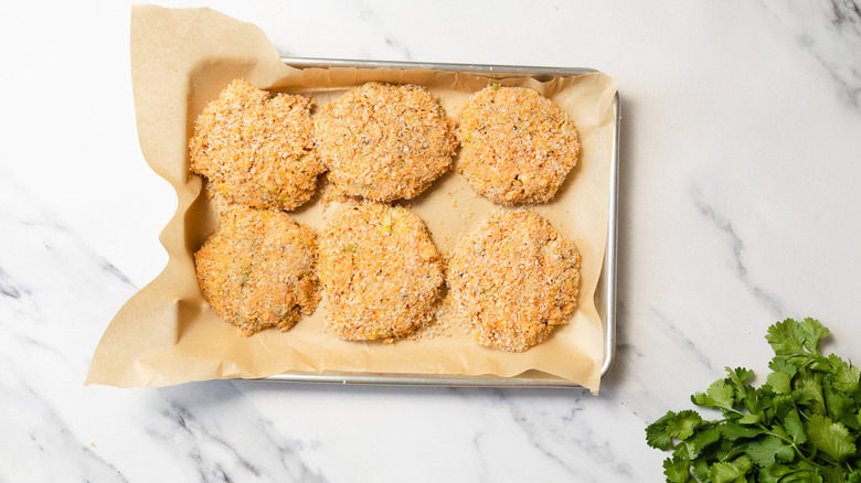 Breadcrumb coated crab cakes on baking sheet