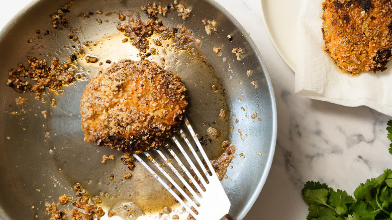 Spatula flipping crab cake in pan