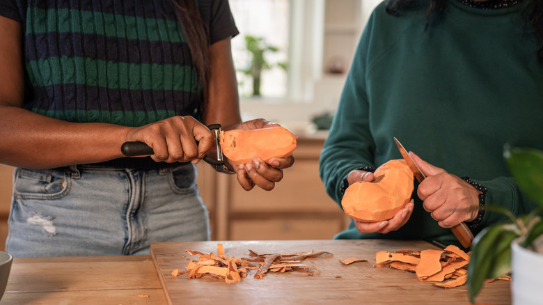 People peeling sweet potatoes at the kitchen counter