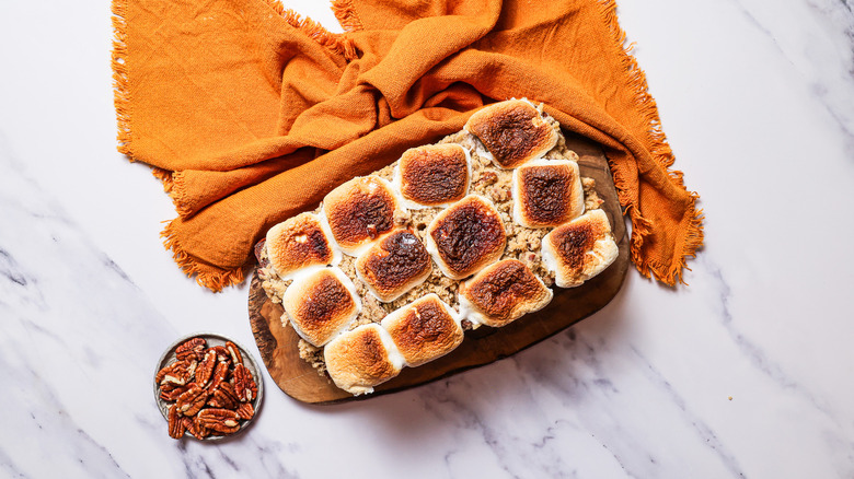 Sweet potato cake on cutting board with pecans on the side