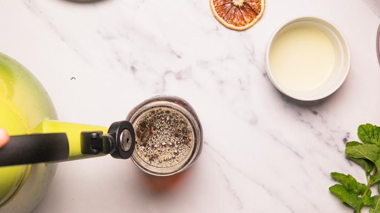 Pouring hot water into glass with tea