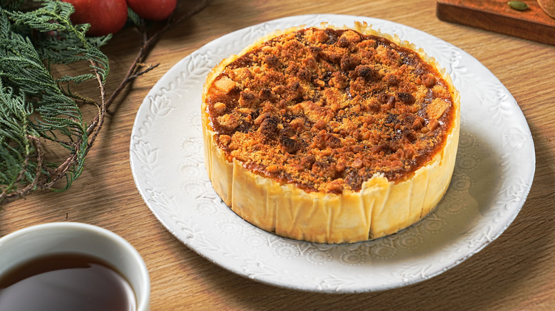 A cinnamon cheesecake on a white plate next to a ramaken of caramel sauce