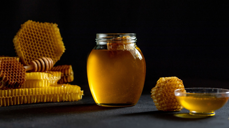 A jar of honey next to honeycomb 