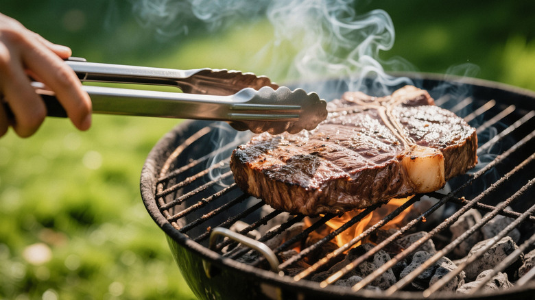T-bone grilling with metal tongs.
