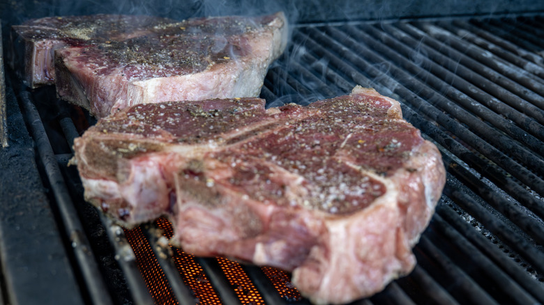 Porterhouse steaks on smoking grill.
