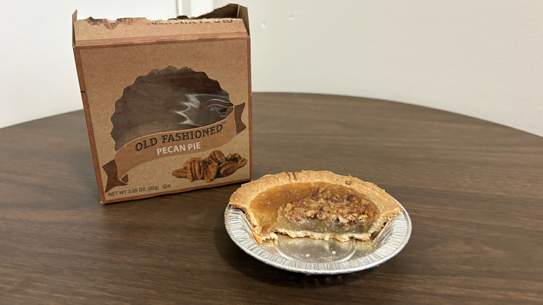 Table Talk pecan pie sliced in half on a aluminum tray next to the box