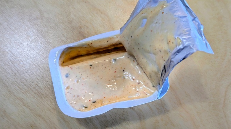 A close-up of an open container of Hidden Valley Diablo Ranch on a light wood table