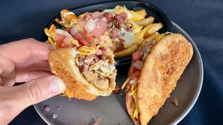 hand holding chalupa over plate of chalupas and nacho fries