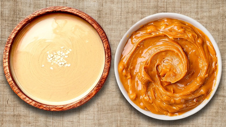 A bowl of tahini beside a bowl of crunchy peanut butter