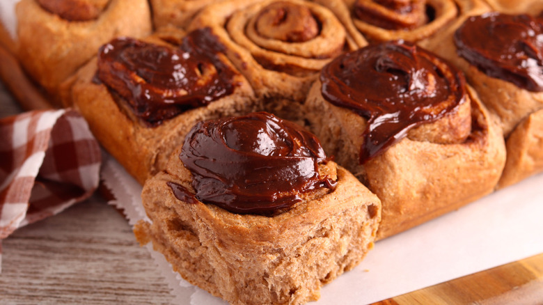 Closeup of baked cinnamon rolls with chocolate ganache topping