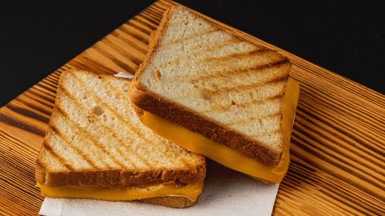 two grilled cheese sandwiches on a wooden platter