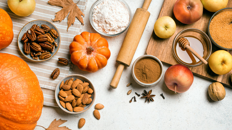 autumnal ingredients like pumpkins, apples, and warm spices laid out with fallen leaves
