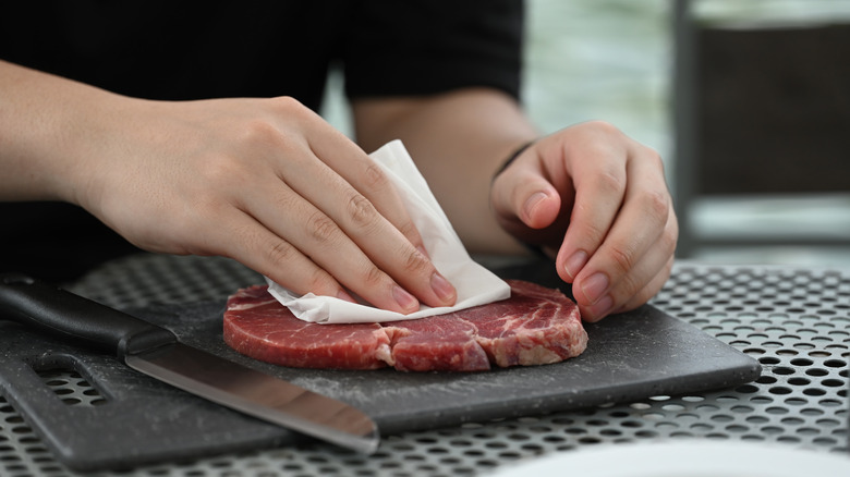 Patting steak dry with paper towel