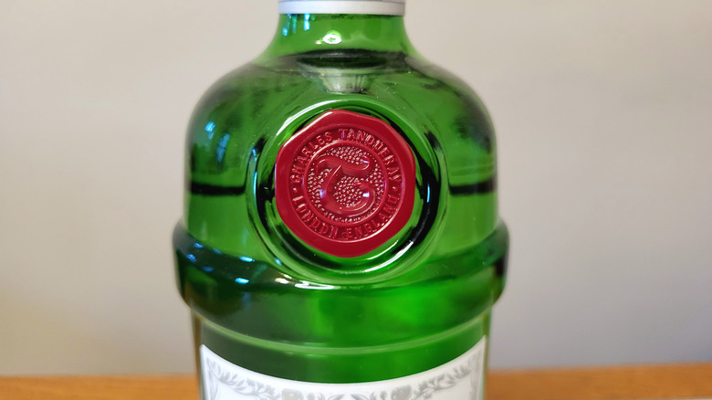 A close-up on the red seal on a green bottle of Tanqueray. The seal reads, "Charles Tanqueray - London, England," with a stylized letter T in the center.