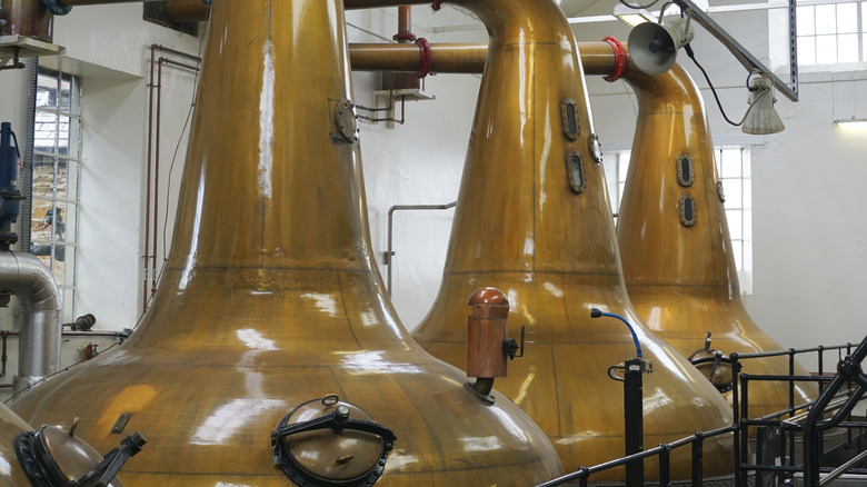 Three copper stills inside a distillery.
