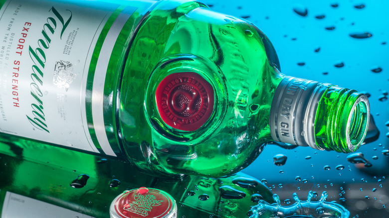 A bottle of Tanqueray lying on its side, surrounded by droplets.