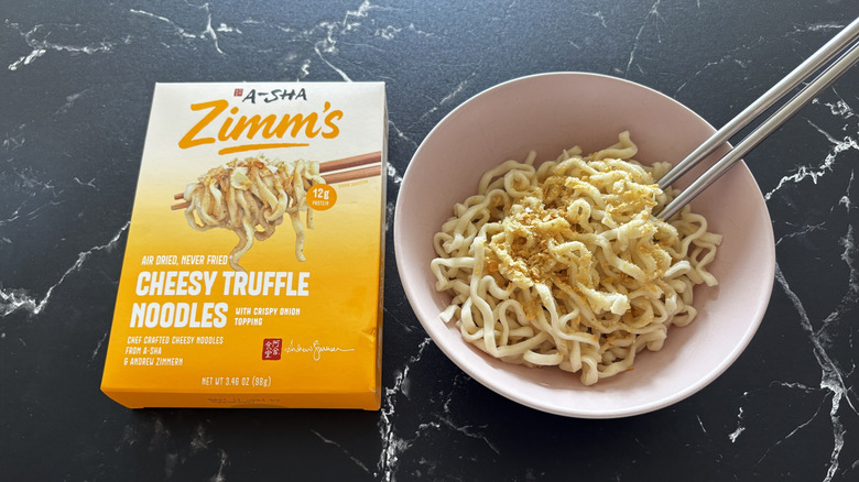 A-Sha/Zimm's cheesy truffle noodles box next to serving of noodles in bowl