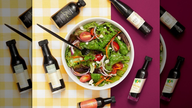 Salad and balsamic vinegar bottles surrounding a salad
