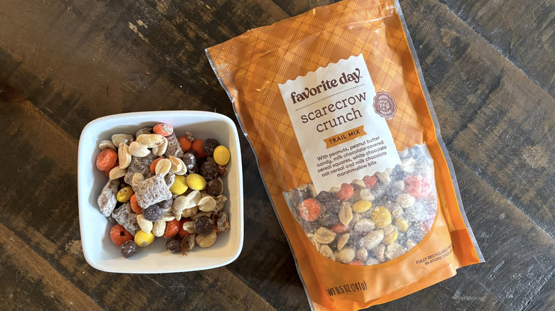 Favorite Day scarecrow crunch trail mix in bag and bowl on wooden table.