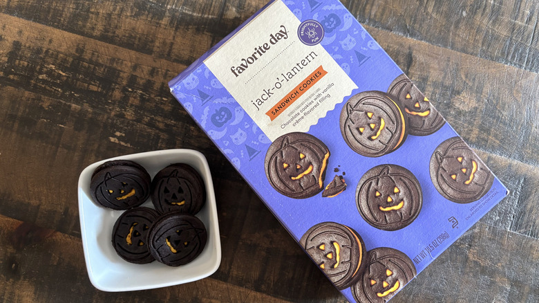 Favorite Day Jack-O-Lantern sandwich cookies in box and bowl on wooden table.
