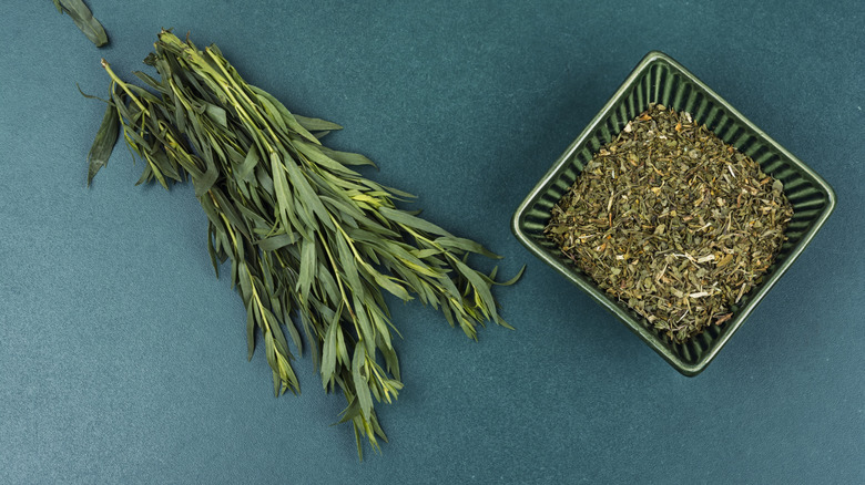 Dried tarragon in bowl next to bunch of fresh tarragon