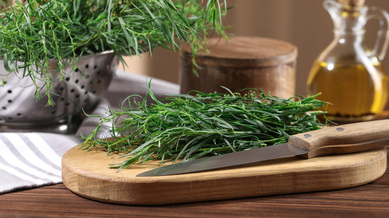 Bunch of fresh tarragon on wooden cutting board with knife