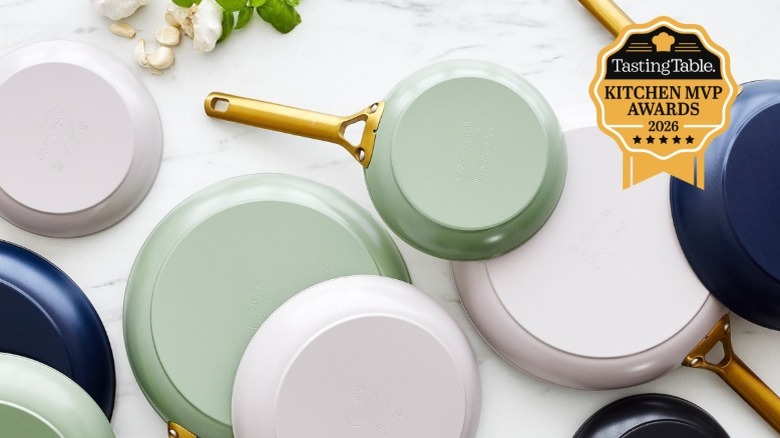 three GreenPan fry pans with gold handles leaning up against a tiled kitchen wall