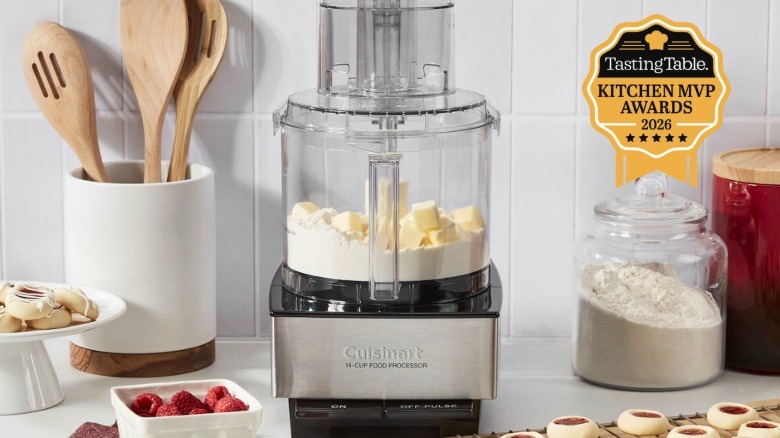 cuisinart food processor with flour and butter inside on table with cookies, fruit, jars, and utensils
