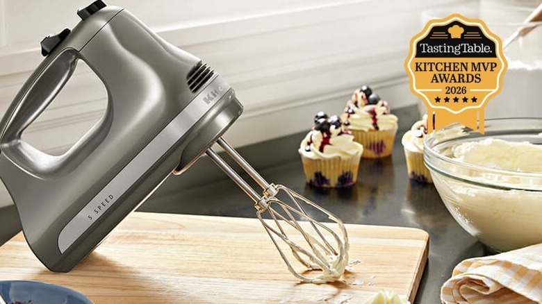 Gray KitchenAid 5-Speed Ultra Power Hand Mixer on cutting board with batter and cupcakes