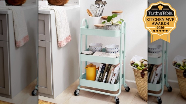 A mint green Amazon Basics 3-Tier Metal Rolling Utility Cart stocked with kitchen items in a kitchen