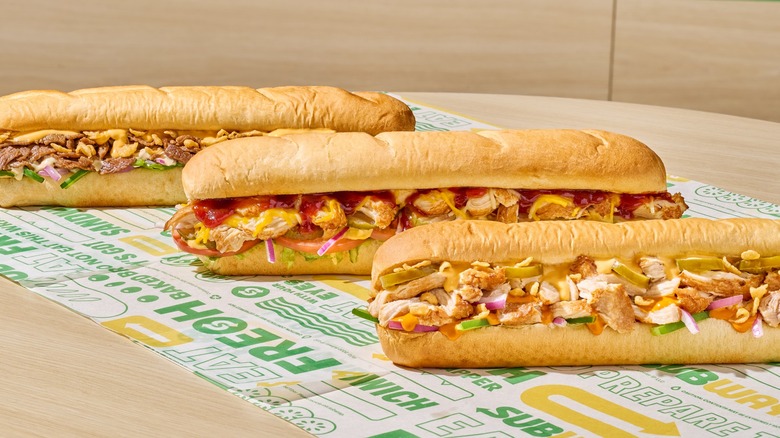 Three Subway restaurant foot-long subs on branded parchment paper