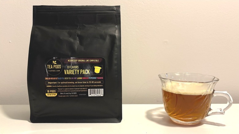 Bag of Tea Boquete tea capsules next to clear brewed cup of tea on white background