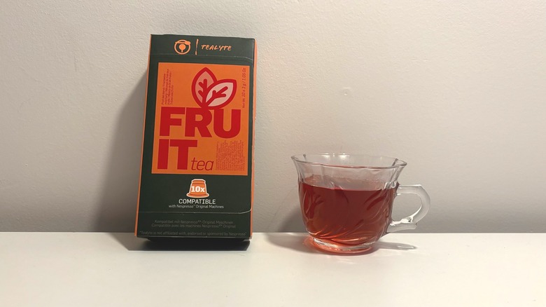 Box of Tealyte fruit tea next to clear cup of brewed tea on white background