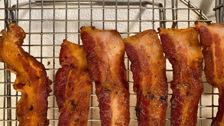cooked slices of bacon cool on a cooling rack