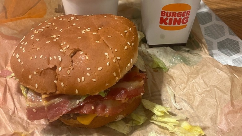 A Texas Double Whopper from Burger King sits next to a drink container and fries.