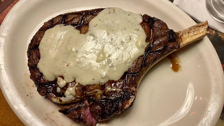 Texas Roadhouse steak with bleu cheese on top on white plate