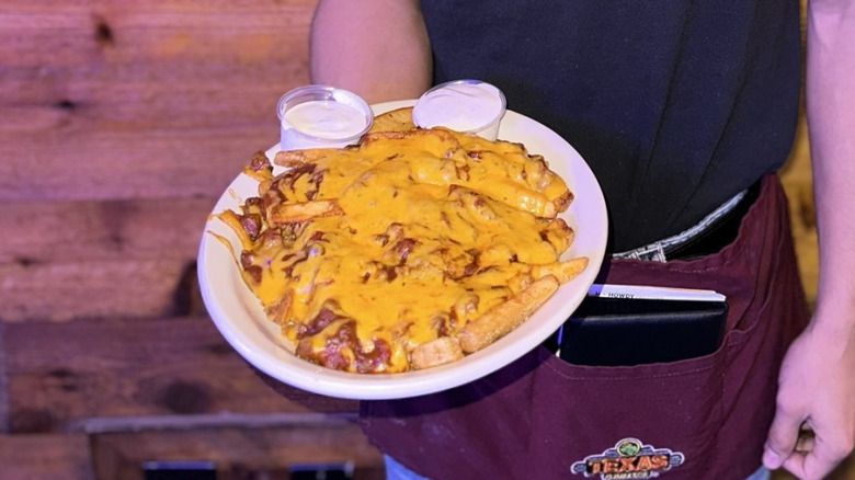 Texas Roadhouse server holding chili cheese fries from the chain