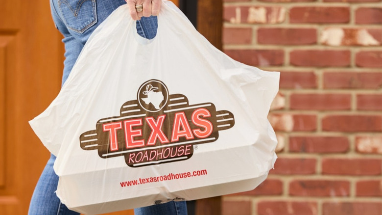 Woman walking with Texas Roadhouse bag